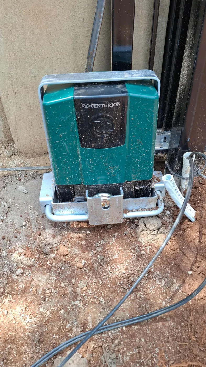 A gate motor mounted on its base plate beside a sliding gate